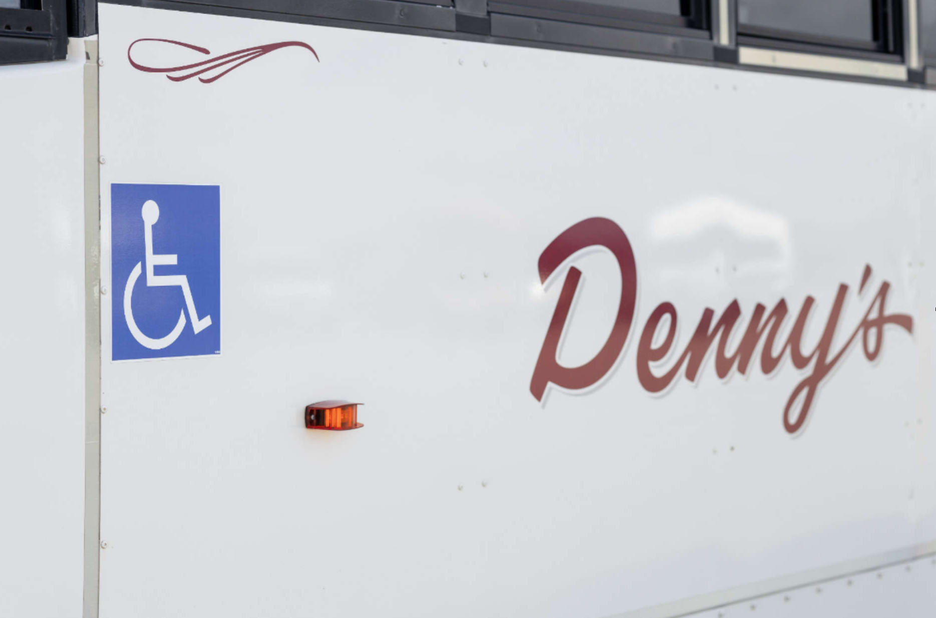 Interior of a wheelchair-accessible Denny’s Bus Lines vehicle with secure mobility seating and passenger accommodations